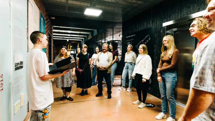 Ryhmä ihmisiä kerääntyneenä puolikaareen kuuntelemaan opastusta